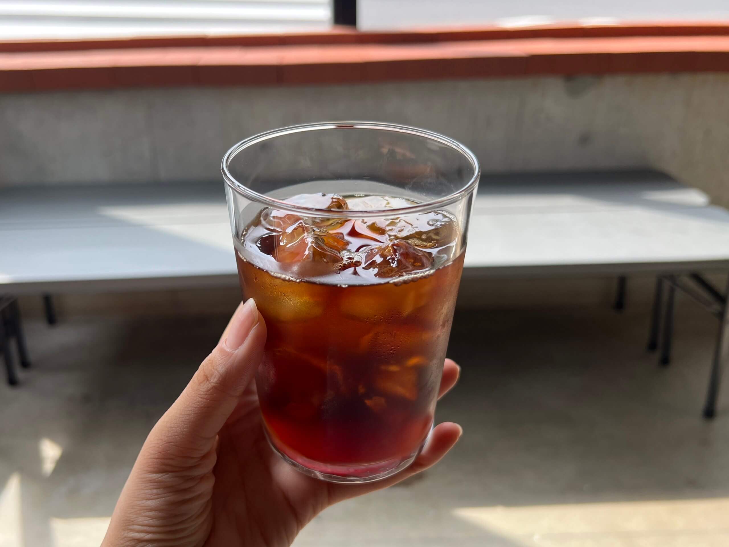 ｈおんとうにおいしいコーヒー店内でアイスコーヒーのグラスを手に持つ