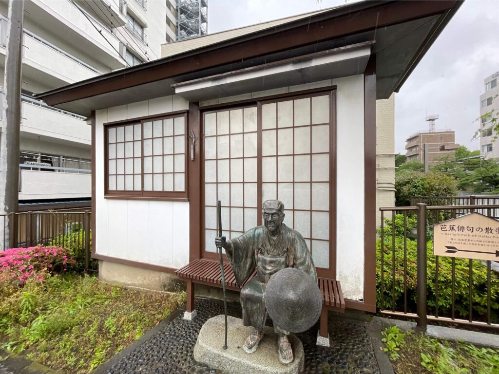 採荼庵跡に設置された松尾芭蕉のブロンズ像と旅の始まりを告げる案内板