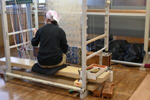 山形緞通の工房で手織りをする職人